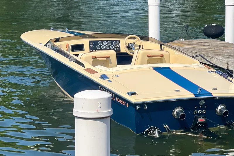 Slide: The Image of 1986 Donzi Hornet III boat docked on calm water, showcasing classic design and vibrant colors. - 3