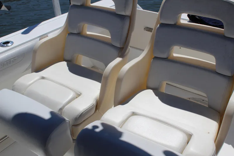 Slide: The Image of 2009 Boston Whaler 220 Outrage boat seats, white and cushioned, on a sunny day. - 19