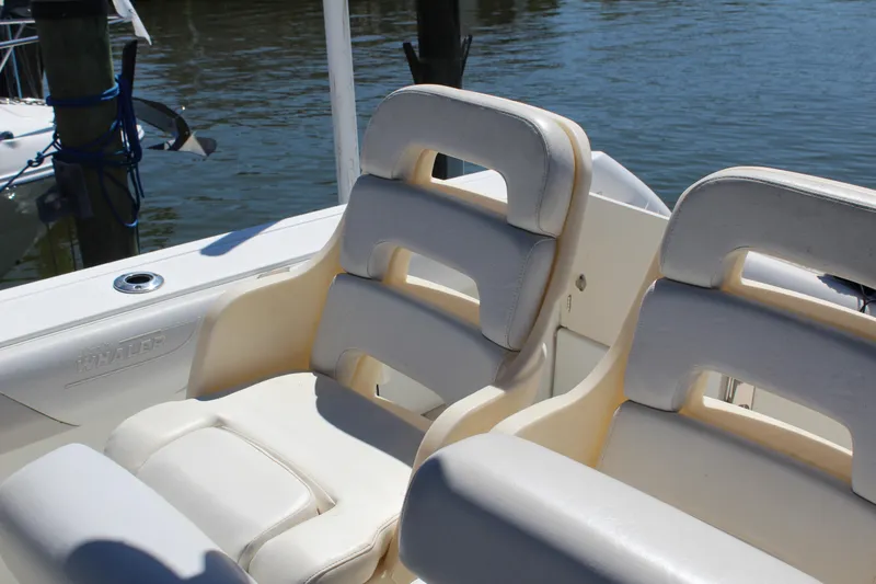 Slide: The Image of 2009 Boston Whaler 220 Outrage boat seats, white leather, docked by water. - 20