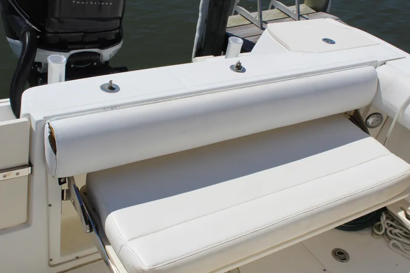 Slide: The Image of 2009 Boston Whaler 220 Outrage boat seat with white upholstery and motor in background. - 6