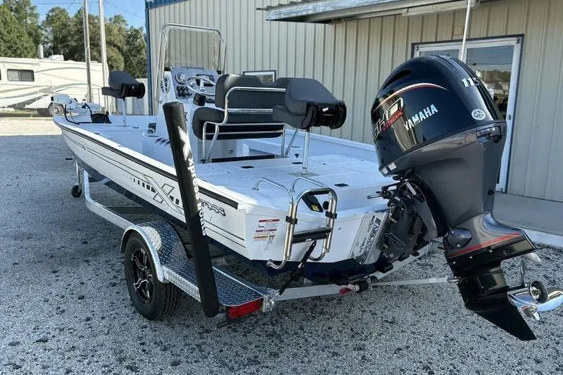 Slide: The Image of 2026 Xpress H20B Bay boat with Yamaha engine on trailer, parked outside a building. - 2
