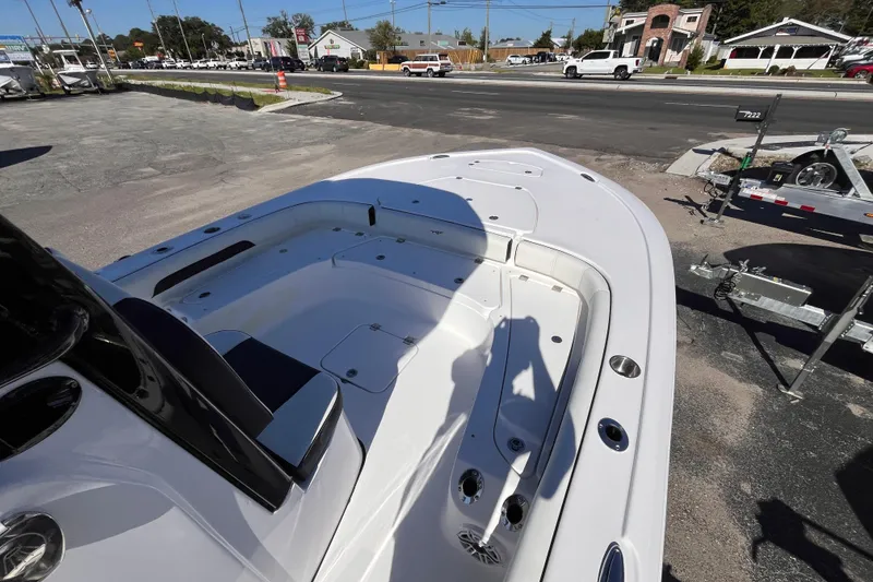 Slide: The Image of 2026 Tidewater 2500 Carolina Bay boat interior with seating and storage, parked outdoors. - 11