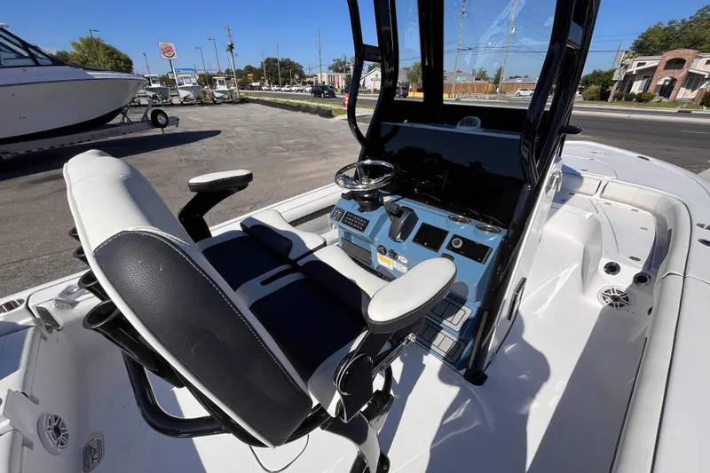 Slide: The Image of 2026 Tidewater 2500 Carolina Bay boat interior with helm and seating, parked outdoors. - 8