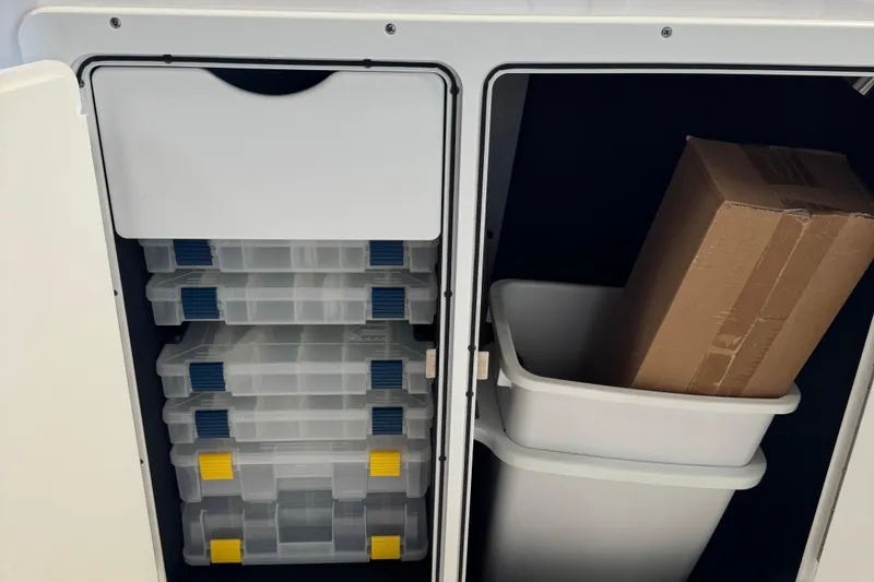 Slide: The Image of Storage compartment in 2024 Yamaha Boats 252 FSH Sport, featuring organized containers and a cardboard box. - 9