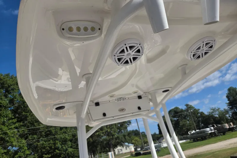 Slide: The Image of 2021 Tidewater 220 LXF boat's T-top with speakers and rod holders, under a clear blue sky. - 10