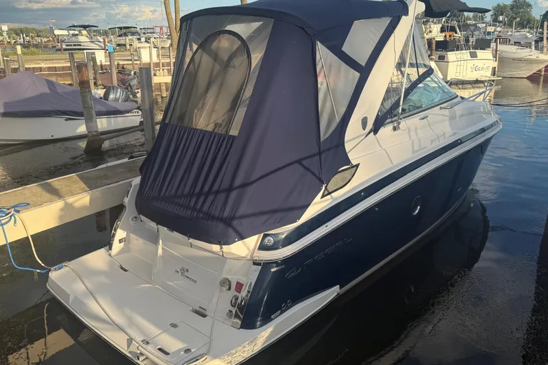 Slide: The Image of 2018 Regal 28 Express boat docked with blue canopy in marina. - 14
