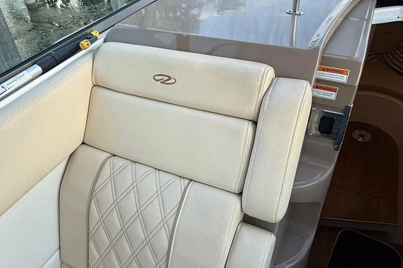 Slide: The Image of 2018 Regal 28 Express boat interior with beige leather seating and safety warnings. - 15
