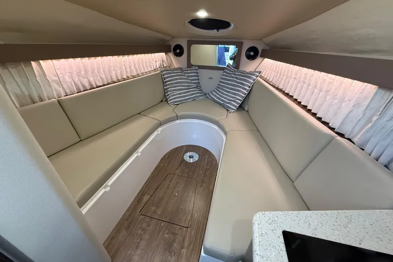 Slide: The Image of 2018 Regal 28 Express cabin interior with beige seating and striped pillows. - 28