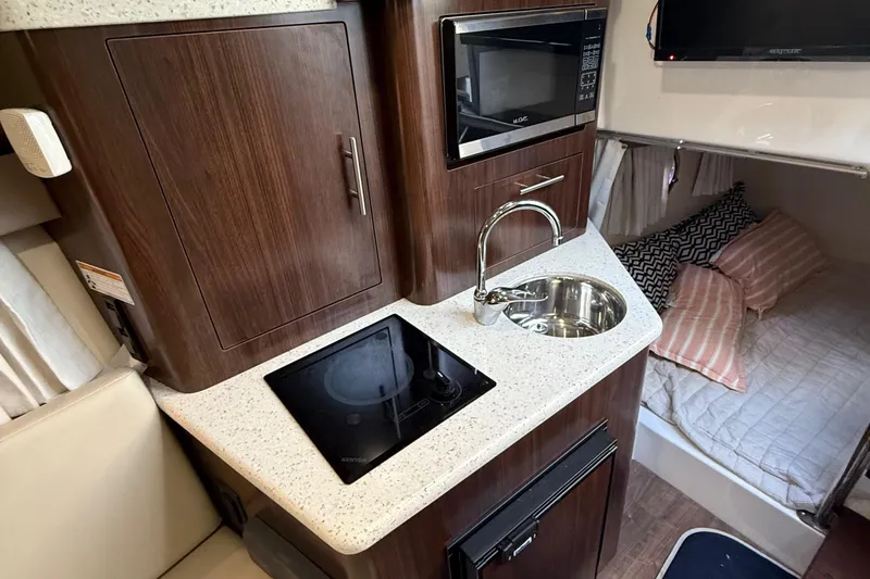 Slide: The Image of 2018 Regal 28 Express boat interior with kitchenette, sink, microwave, and cozy sleeping area. - 36