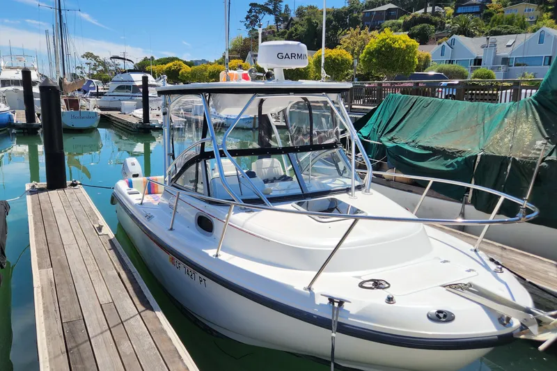The Image of 2000 Boston Whaler 21 Conquest boat docked in a marina under clear blue skies. - 0