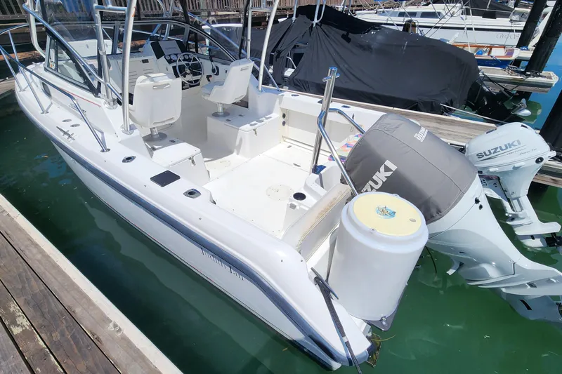 Slide: The Image of 2000 Boston Whaler 21 Conquest boat docked, featuring Suzuki outboard motor. - 6