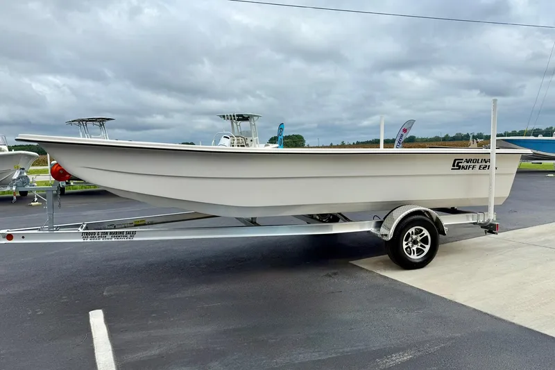 Slide: The Image of 2026 Carolina Skiff E21 DLX Kit Boat on trailer, parked outdoors under cloudy sky. - 3