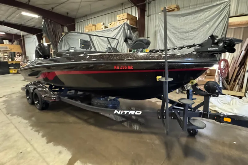 Slide: The Image of 2024 Nitro ZV21 boat in warehouse, black with red accents, on trailer. - 2