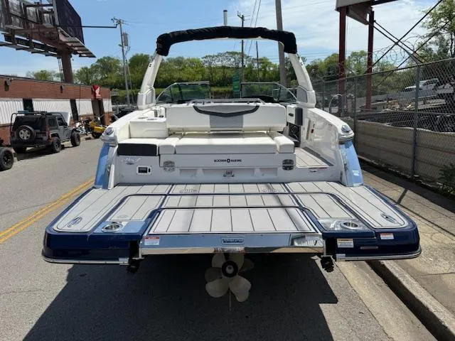 Slide: The Image of 2023 Chaparral 267 SSX boat, rear view, parked on street, showcasing swim platform and seating. - 32