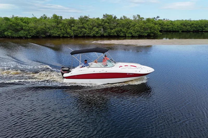 The Image of 2015 Hurricane SunDeck 2200 OB cruising on a calm river with lush greenery. - 0