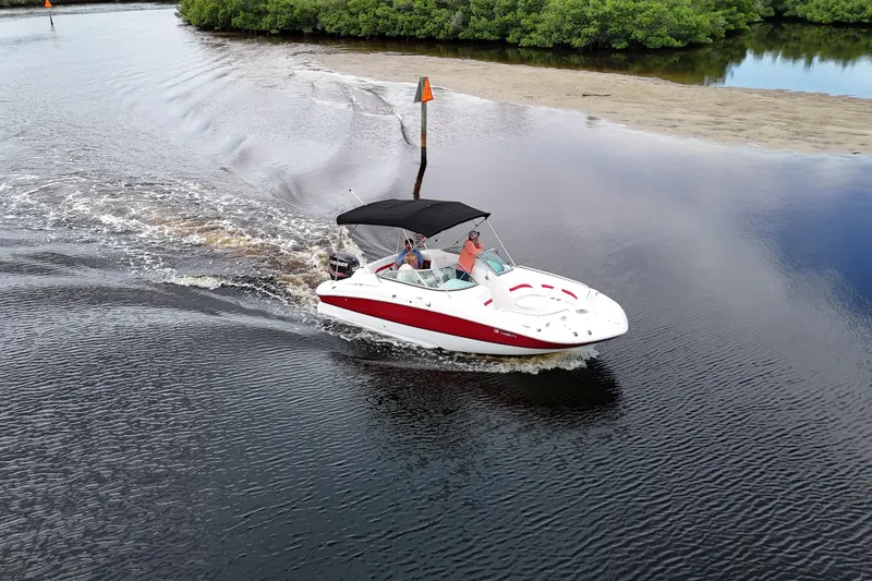 Slide: The Image of 2015 Hurricane SunDeck 2200 OB cruising on a calm river with lush greenery. - 1