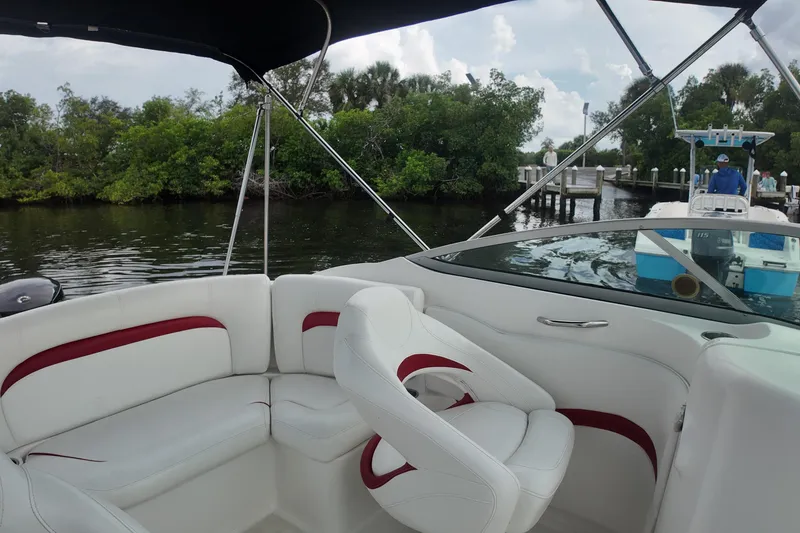 Slide: The Image of 2015 Hurricane SunDeck 2200 OB boat interior with white and red seating, dockside view. - 19