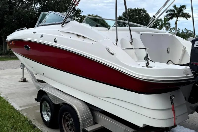 Slide: The Image of 2015 Hurricane SunDeck 2200 OB boat on trailer, red and white design, parked outdoors. - 21