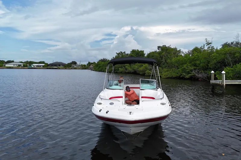 Slide: The Image of 2015 Hurricane SunDeck 2200 OB boat on calm water, surrounded by lush greenery. - 6