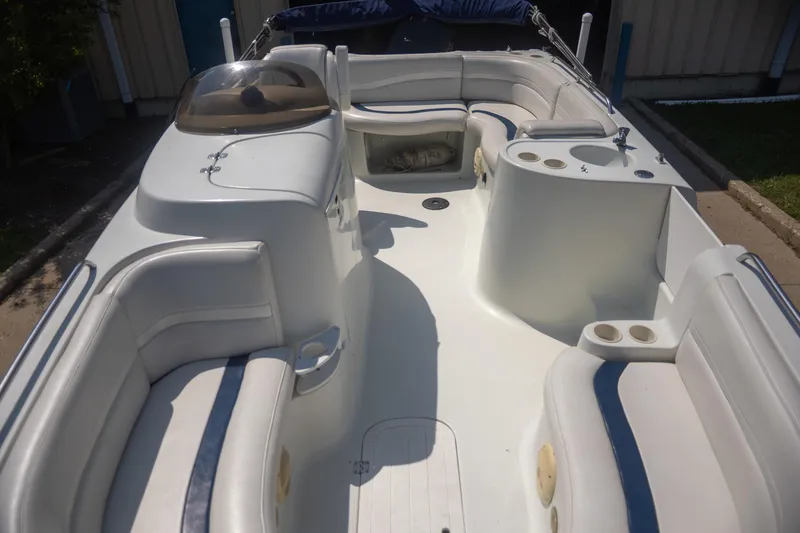Slide: The Image of 2002 Starcraft AUORA 229 STEP CC DECK boat interior with white seating and cup holders. - 10
