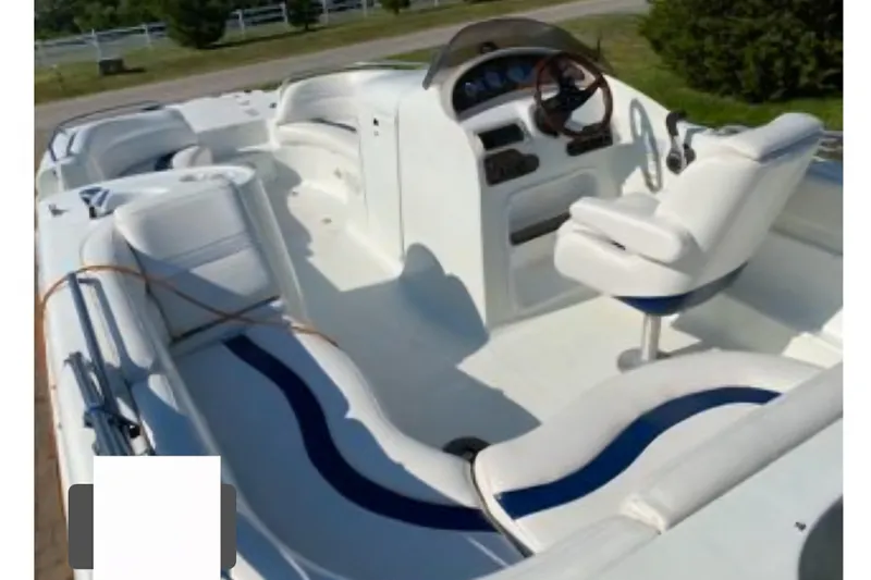 Slide: The Image of 2002 Starcraft AUORA 229 STEP CC DECK boat interior with white seating and steering console. - 7
