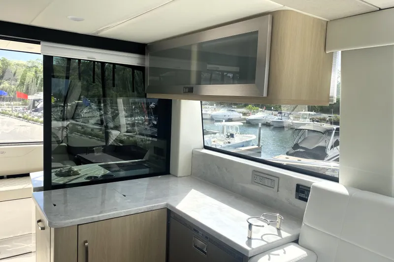 Slide: The Image of 2023 Regal 38 Grande Coupe yacht interior with modern kitchenette and marina view. - 11