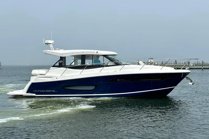 Slide: The Image of 2023 Regal 38 Grande Coupe yacht cruising on calm waters. - 2