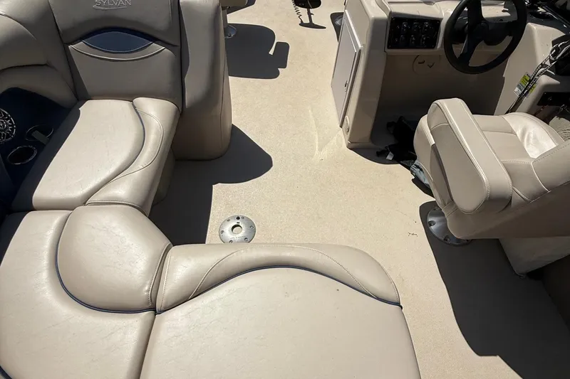 Slide: The Image of 2016 Sylvan Mirage Fish 8520 4-PT boat interior with beige seating and steering console. - 28