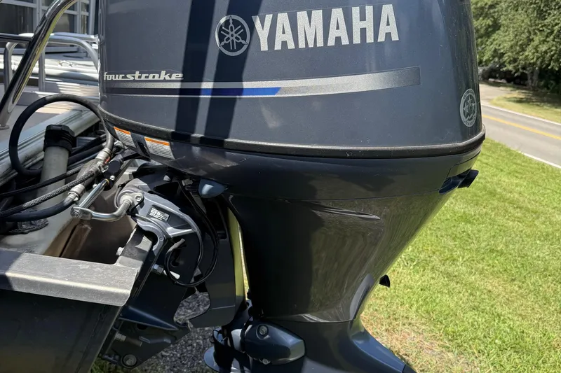 Slide: The Image of Yamaha four-stroke engine on 2016 Sylvan Mirage Fish 8520 4-PT boat, parked on grass. - 4