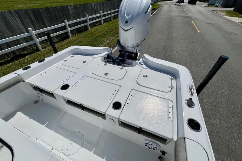 Slide: The Image of 2025 Sea Hunt BX 25 FS boat deck with storage compartments and motor, parked on a road. - 8