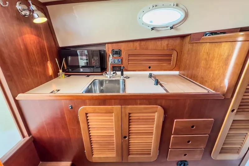 Slide: The Image of Hinckley Yachts 2001 Picnic Boat Classic 36 interior galley with sink, microwave, and wooden cabinetry. - 19