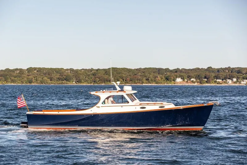 Slide: The Image of 2001 Hinckley Yachts Picnic Boat Classic 36 cruising on open water, with scenic shoreline backdrop. - 4