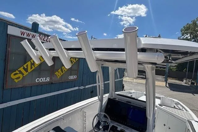 Slide: The Image of 2026 Yamaha Boats 255 FSH Sport H with rod holders, displayed outdoors. - 24