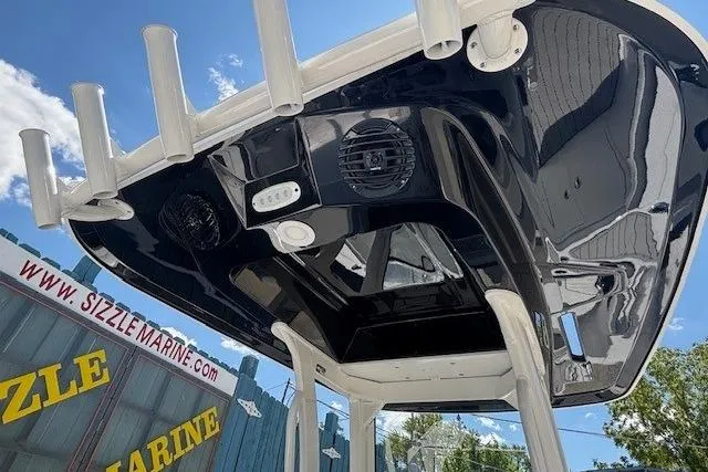 Slide: The Image of 2026 Yamaha Boats 255 FSH Sport H, sleek black canopy, rod holders, outdoor setting. - 25