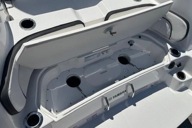 Slide: The Image of 2026 Yamaha Boats 255 FSH Sport H open storage compartment with cup holders and sleek design. - 36