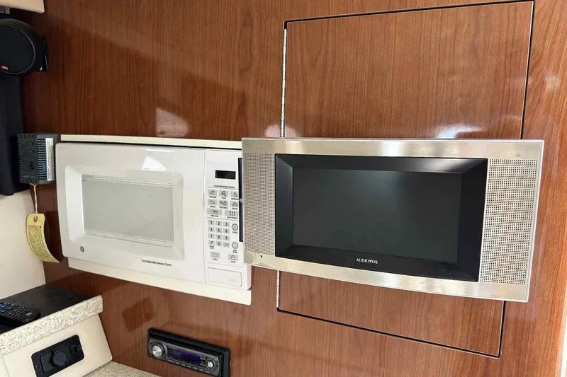 Slide: The Image of 2005 Regal 3350 Sport Cruiser interior with microwave and Audiovox TV on wood paneling. - 23