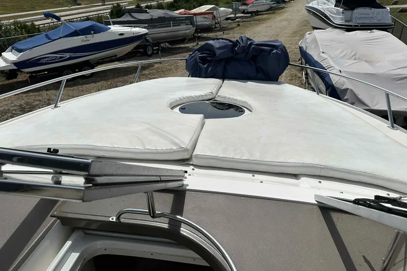 Slide: The Image of 2005 Regal 3350 Sport Cruiser boat deck with sunpad and railing, parked among other boats. - 35