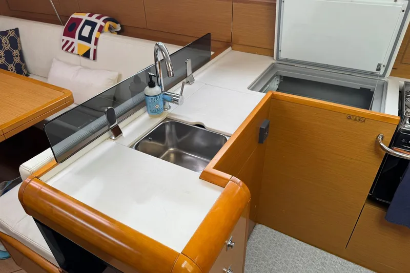 Slide: The Image of Modern kitchen area in a 2013 Jeanneau 409 sailboat, featuring a sink and open fridge. - 25