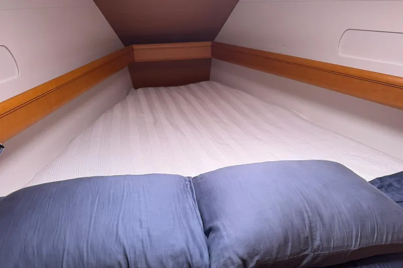 Slide: The Image of Cozy cabin bed in 2013 Jeanneau 409 sailboat with wooden accents and blue bedding. - 33