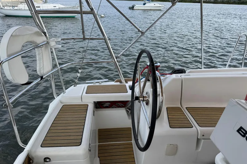 Slide: The Image of Jeanneau 409 sailboat cockpit with steering wheel and teak seating, docked on calm water. - 6