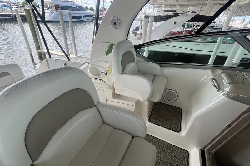Slide: The Image of 2004 Sea Ray 340 Sundancer interior with plush seating and helm, docked at marina. - 10