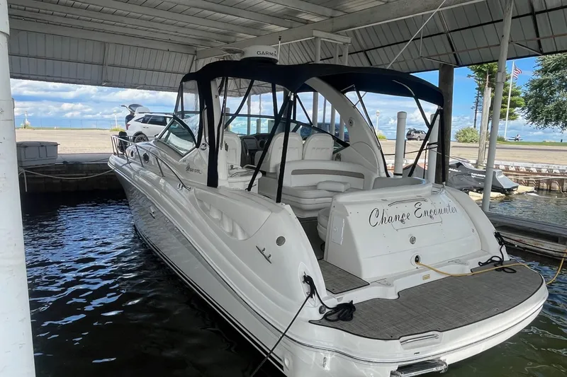 Slide: The Image of 2004 Sea Ray 340 Sundancer docked under a covered marina, featuring sleek design and spacious seating. - 2