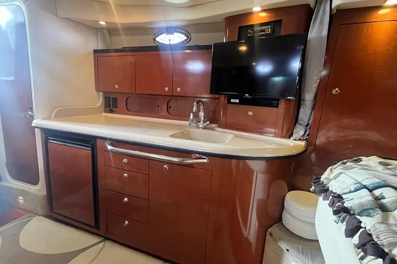 Slide: The Image of 2004 Sea Ray 340 Sundancer interior with kitchenette, TV, and wooden cabinetry. - 23