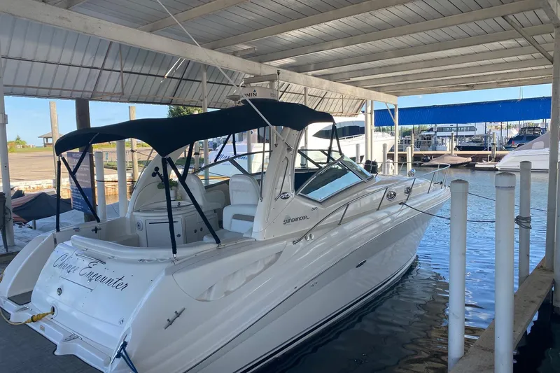 Slide: The Image of 2004 Sea Ray 340 Sundancer docked under a covered marina, featuring sleek design and canopy. - 5