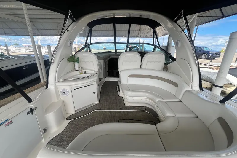 Slide: The Image of 2004 Sea Ray 340 Sundancer interior with white seating and helm, docked at marina. - 7