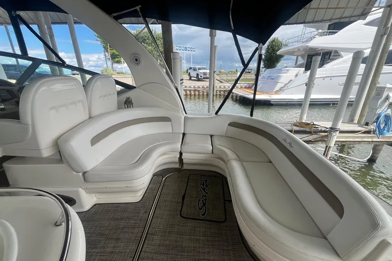 Slide: The Image of 2004 Sea Ray 340 Sundancer boat interior with white seating and marina view. - 8