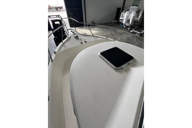 Slide: The Image of 1997 Pursuit 2870 Walkaround boat deck with hatch, in a storage facility. - 12