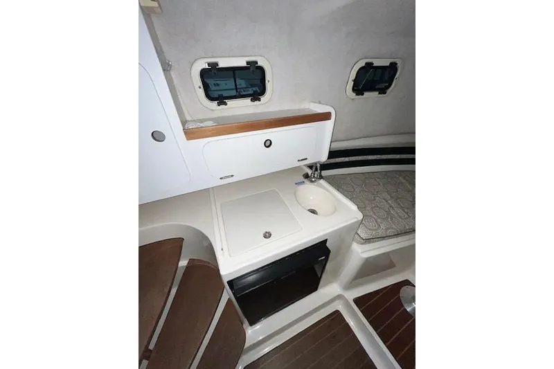 Slide: The Image of 1997 Pursuit 2870 Walkaround cabin interior with sink, storage, and seating area. - 20
