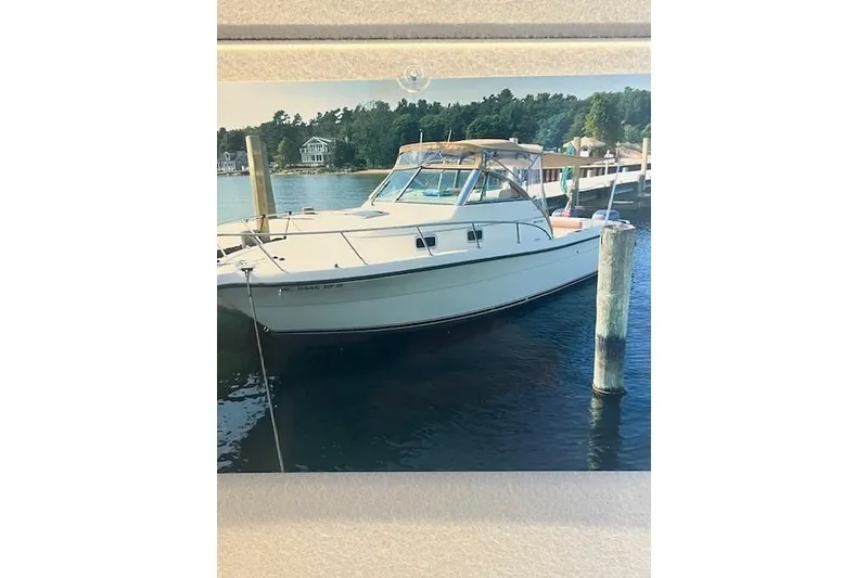 Slide: The Image of 1997 Pursuit 2870 Walkaround boat docked in a serene marina setting. - 3
