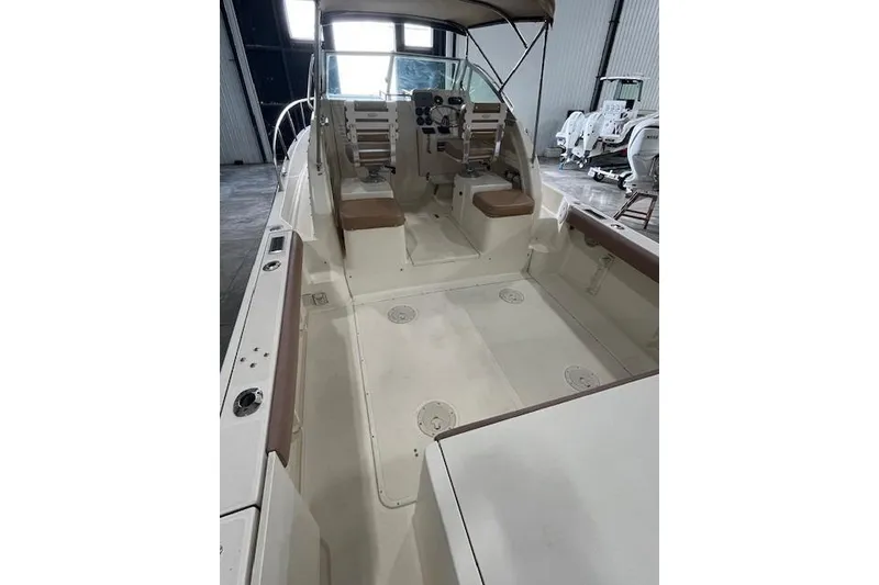 Slide: The Image of 1997 Pursuit 2870 Walkaround boat interior with seating and control panel in a warehouse. - 7